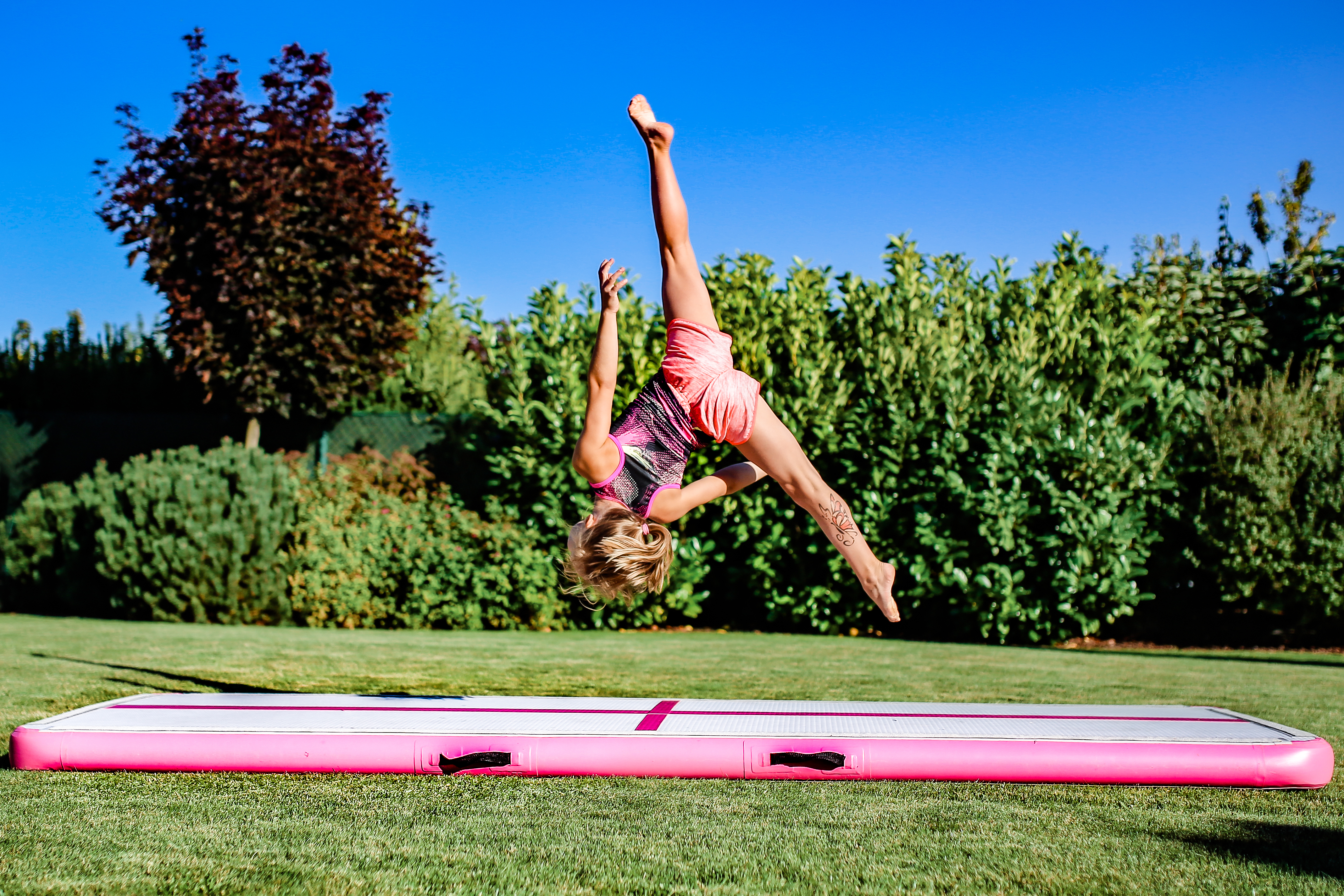 Dívka skáče hvězdu bez rukou na airtracku MASTER na zahradě